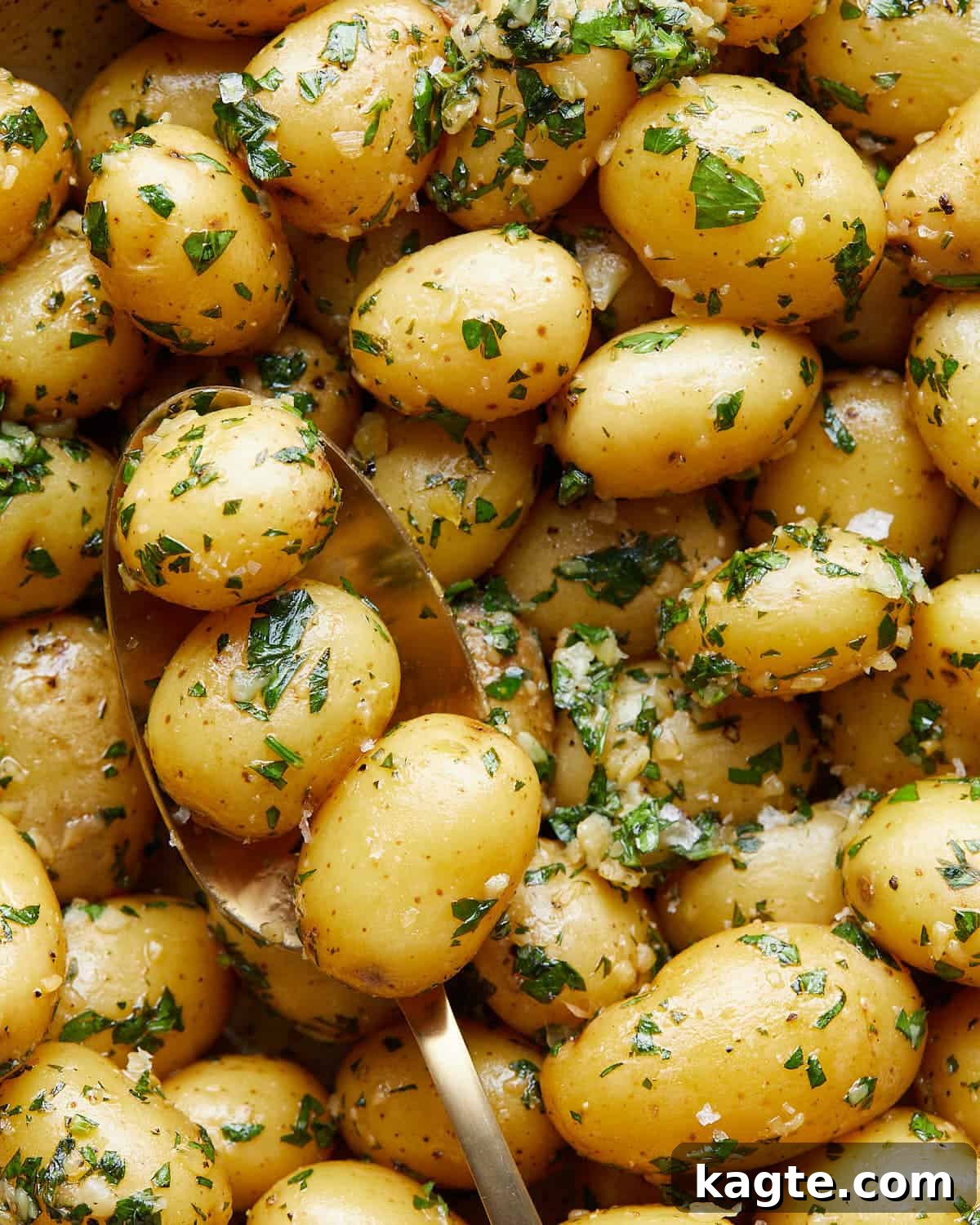 Up close image of garlic parsley potatoes in a serving bowl, showing the herbs and butter.