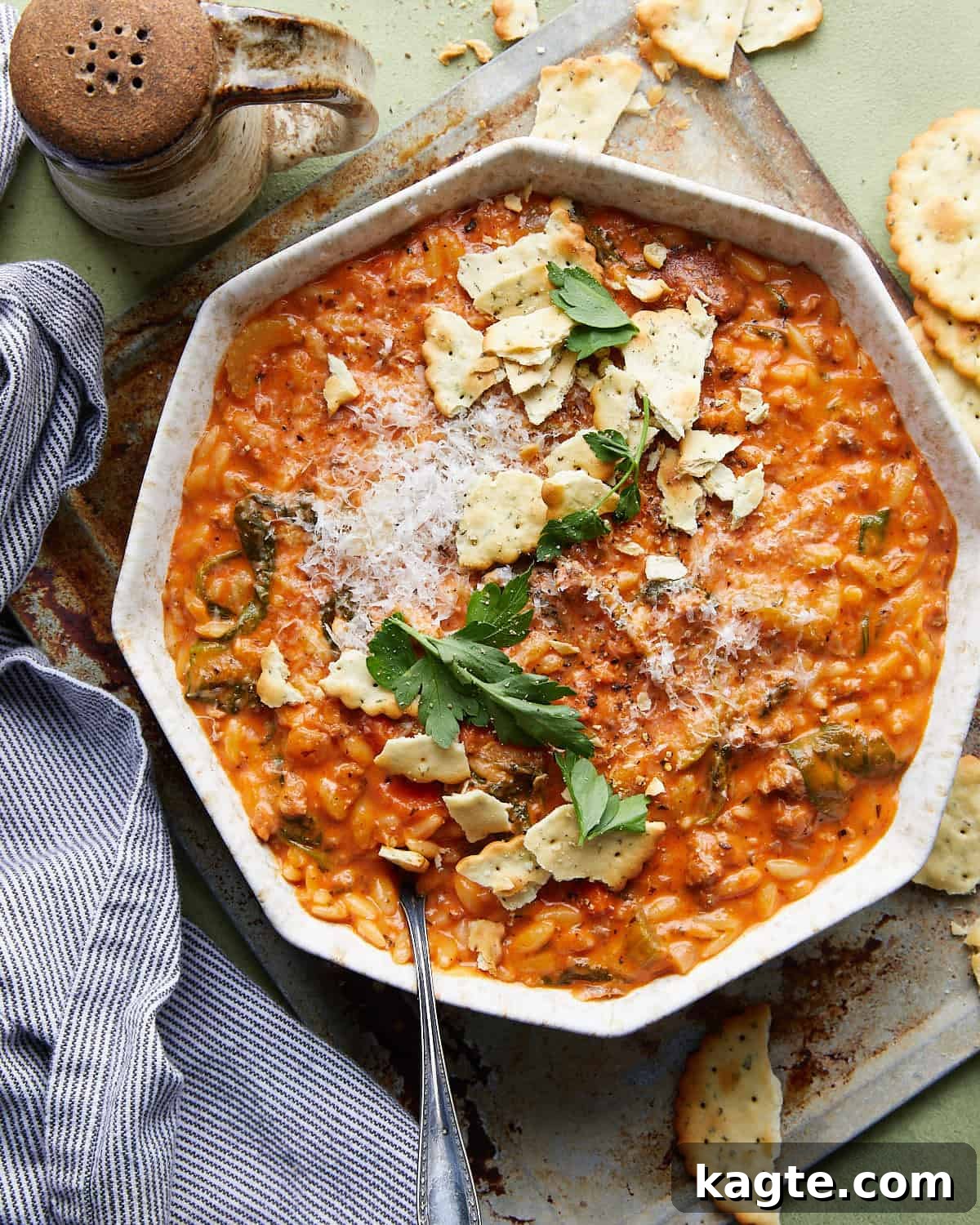 Hearty Creamy Italian Sausage Soup with Orzo and Kale 2 Overhead image of a bowl of creamy Italian sausage soup, garnished with fresh parsley and grated Parmesan cheese, with crusty bread on the side.