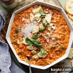 A bowl of Creamy Italian Sausage Soup with Orzo and Kale, garnished with fresh herbs.