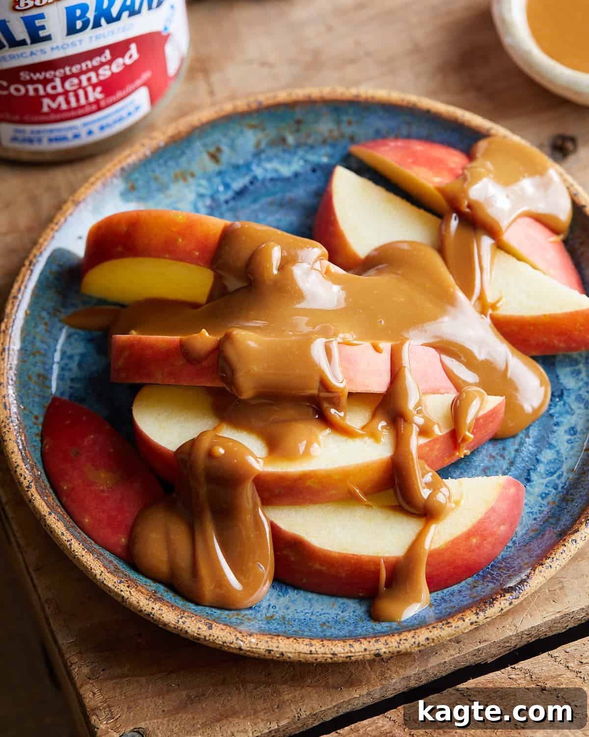 Overhead image of decadent homemade caramel sauce drizzled on fresh red apple slices, inviting a sweet and healthy snack idea.