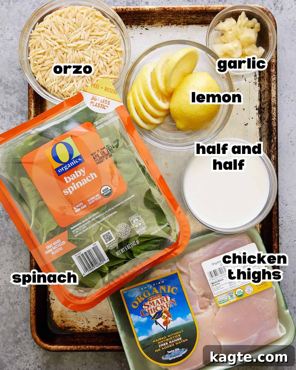 One-Pan Zesty Lemon Chicken Orzo 3 Overhead flat lay image of all the fresh ingredients needed to prepare one pot lemon chicken with orzo, including chicken thighs, lemons, garlic, spinach, orzo, and cream.