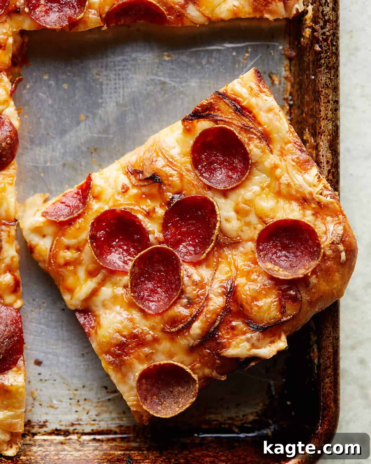Up close image of crispy pepperoni sheet pan pizza, highlighting the texture of the crust and melted cheese.