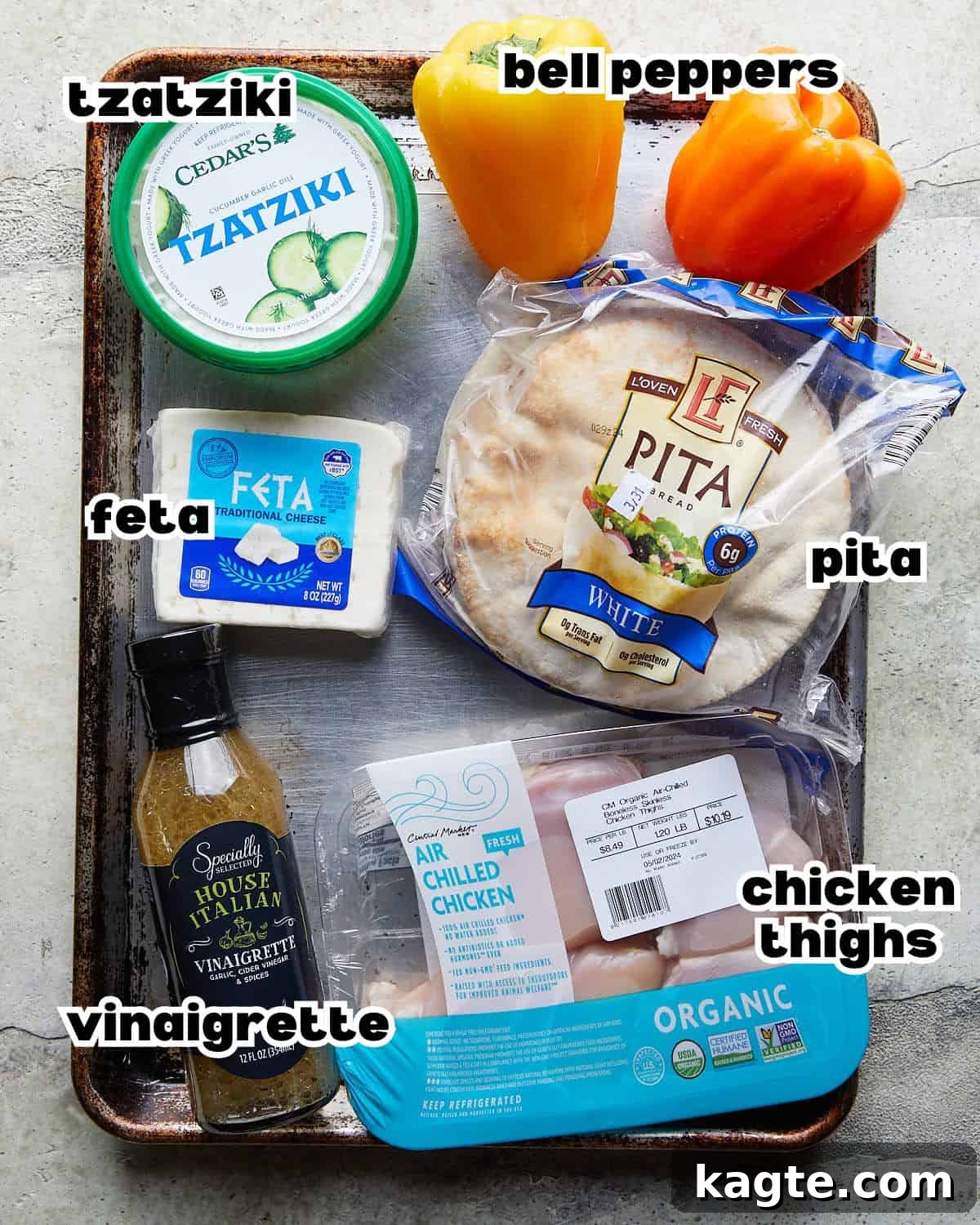 Quick Chicken Pita Sandwiches 3 Overhead image of fresh ingredients needed to make chicken pita pockets, including chicken, bell peppers, feta, tzatziki, pita bread, and Italian dressing.