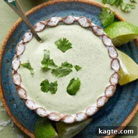 A creamy, pale green poblano cream sauce garnished with fresh cilantro in a white bowl.