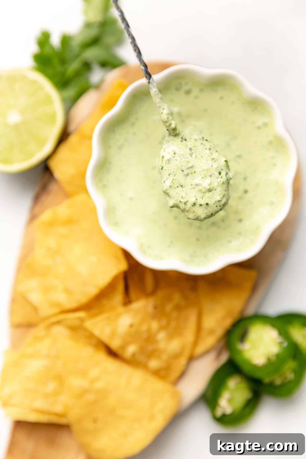 Zesty Jalapeño Lime Crema 2 A close-up shot of creamy Jalapeño Lime Crema on a spoon, showcasing its smooth texture and subtle green hues, ready to be drizzled over a dish.