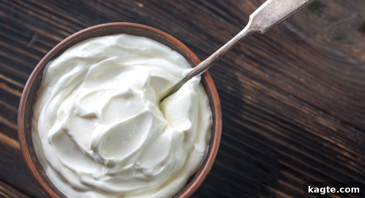 Top 12 Orange Juice Substitutes for Cooking and Baking 11 Overhead image of a bowl of creamy plain yogurt with a spoon resting inside, suggesting a healthy and versatile ingredient.