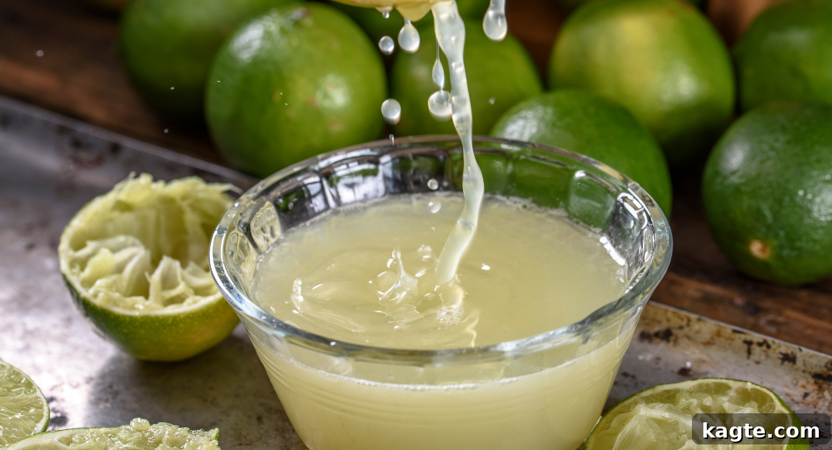 Top 12 Orange Juice Substitutes for Cooking and Baking 4 Close-up image of fresh lime juice in a clear glass, with sliced and whole green limes artfully arranged in the background, highlighting its vibrant nature.