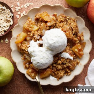 Close-up of baked Dutch Oven Apple Crisp with a scoop missing and ice cream on top.