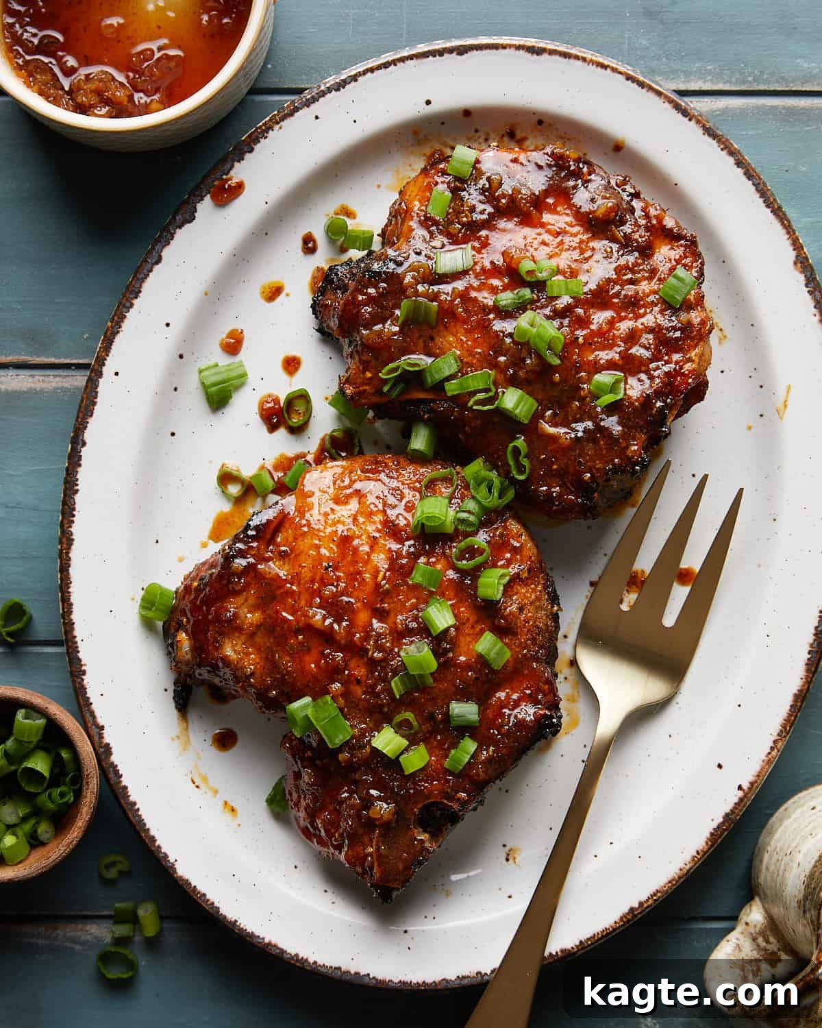 Overhead image of honey glazed pork chops with fresh herb garnish, showcasing their beautiful golden-brown color and sticky glaze.