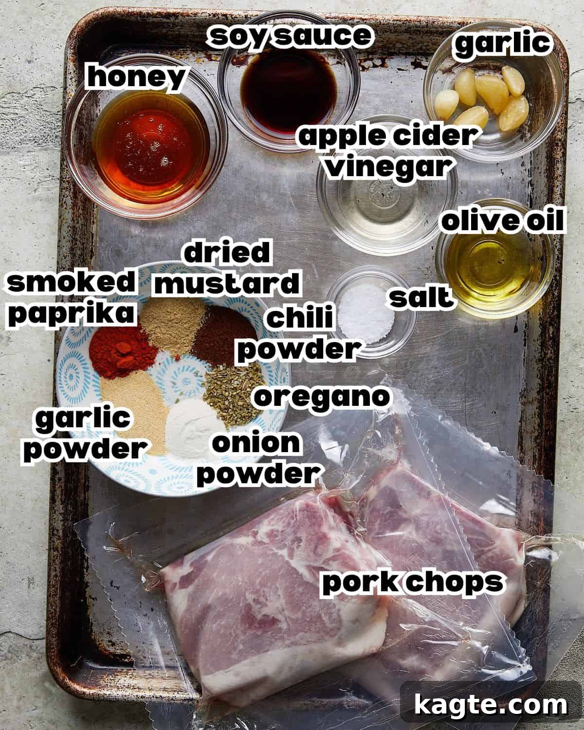 Overhead image of fresh ingredients neatly arranged on a counter, including raw pork chops, honey, apple cider vinegar, soy sauce, and a selection of spices.