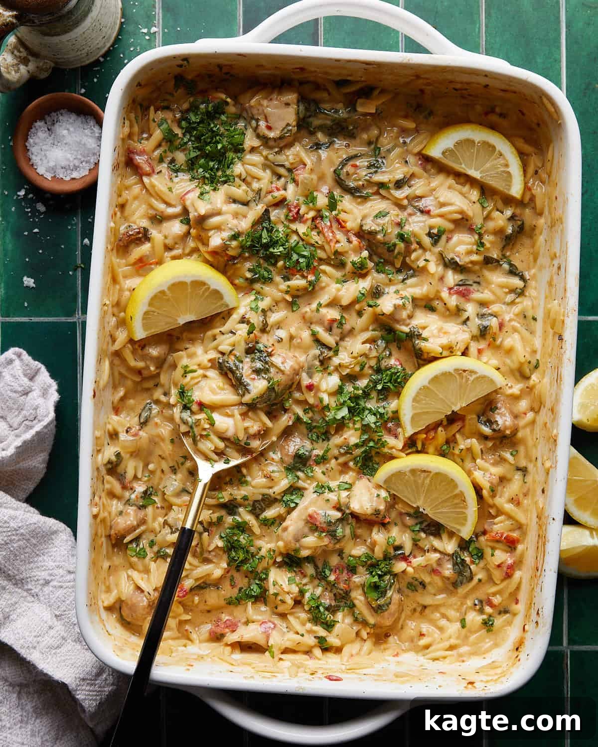 Creamy Tuscan Chicken Orzo Casserole 2 Overhead image of chicken and orzo bake in white baking dish with fresh parsley garnish.