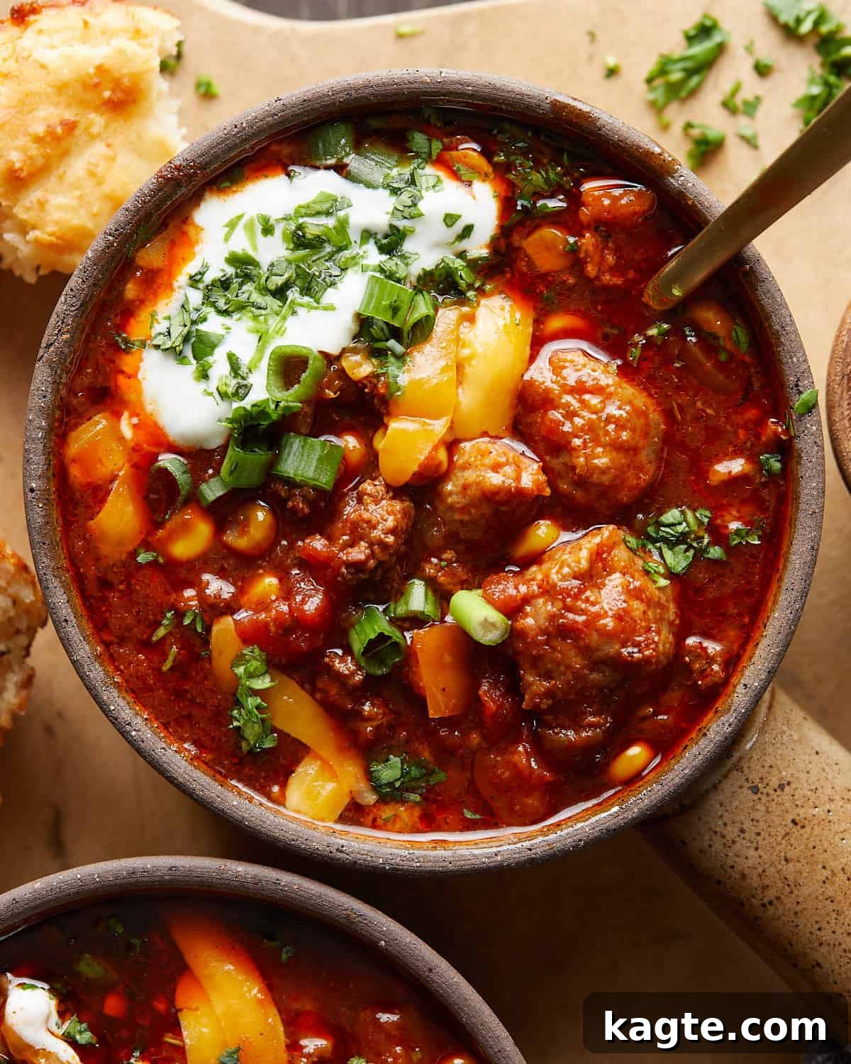 No-Fuss Slow Cooker Beanless Chili 5 Close-up overhead image of a steaming bowl of slow cooker no bean chili, richly garnished with sour cream, shredded cheese, and fresh cilantro, ready to be enjoyed.