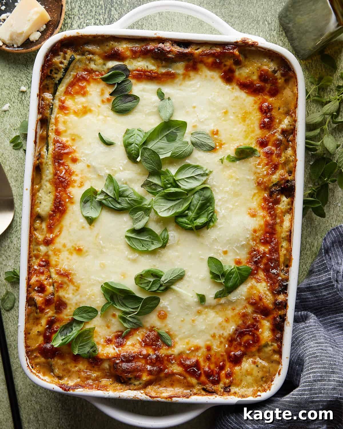 Overhead image of veggie lasagna with white sauce and garnish, showcasing its vibrant colors and creamy texture.
