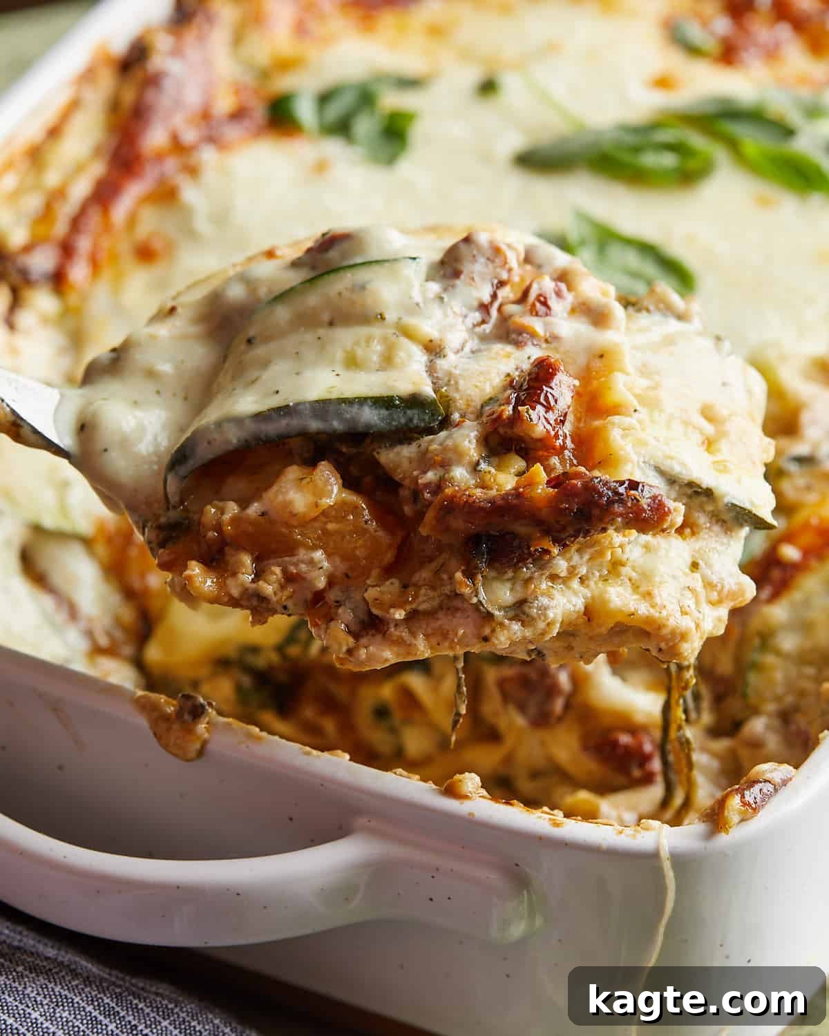 Side view of a slice of veggie lasagna with white sauce, showing its distinct layers and golden-brown top.