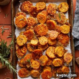 Close-up of crispy, cheesy savory roasted sweet potatoes, garnished with fresh rosemary.