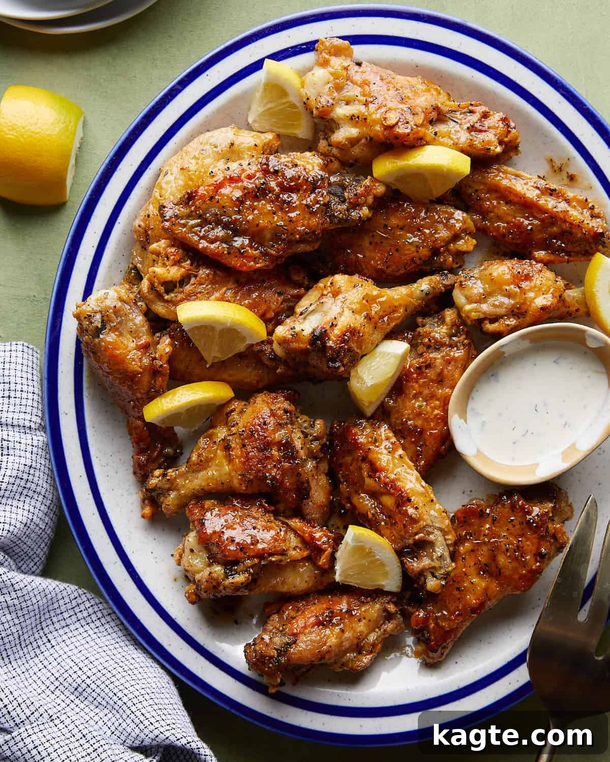Honey Glazed Lemon Pepper Wings 2 Overhead image of golden brown honey lemon pepper wings garnished with lemon wedges, fresh parsley, and a side of creamy ranch dressing, ready to be served.