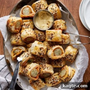 Close-up of golden brown chicken sausage rolls on a white plate, garnished with fresh herbs, ready to be served.