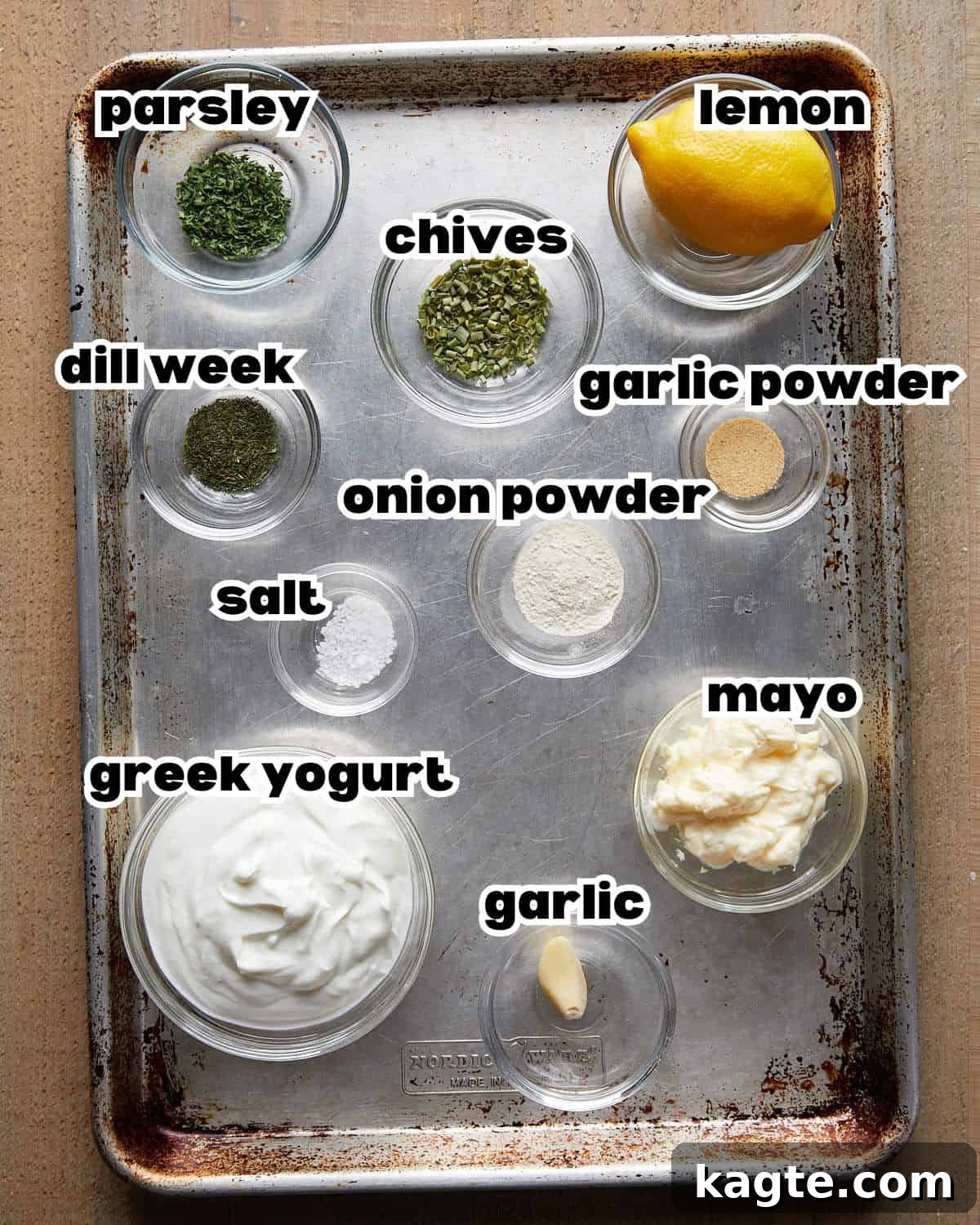 Tangy Greek Ranch Creation 3 Overhead image of fresh ingredients for homemade greek yogurt ranch dressing, including lemon, garlic, herbs, and a bowl of Greek yogurt.