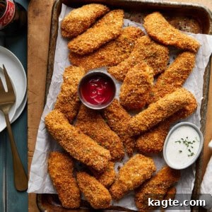 A serving of crispy chicken tenders with a side of dipping sauce.