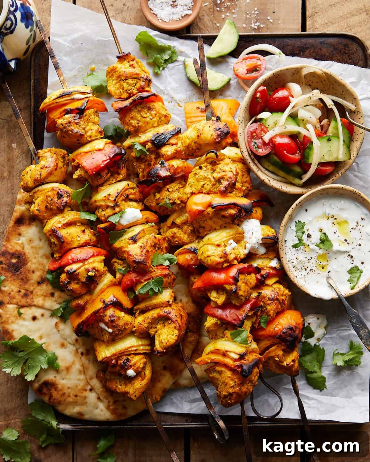 Simple Oven Roasted Chicken Kabobs 2 Overhead image of golden brown chicken kabobs with fresh herbs and dips on the side, ready to be served.