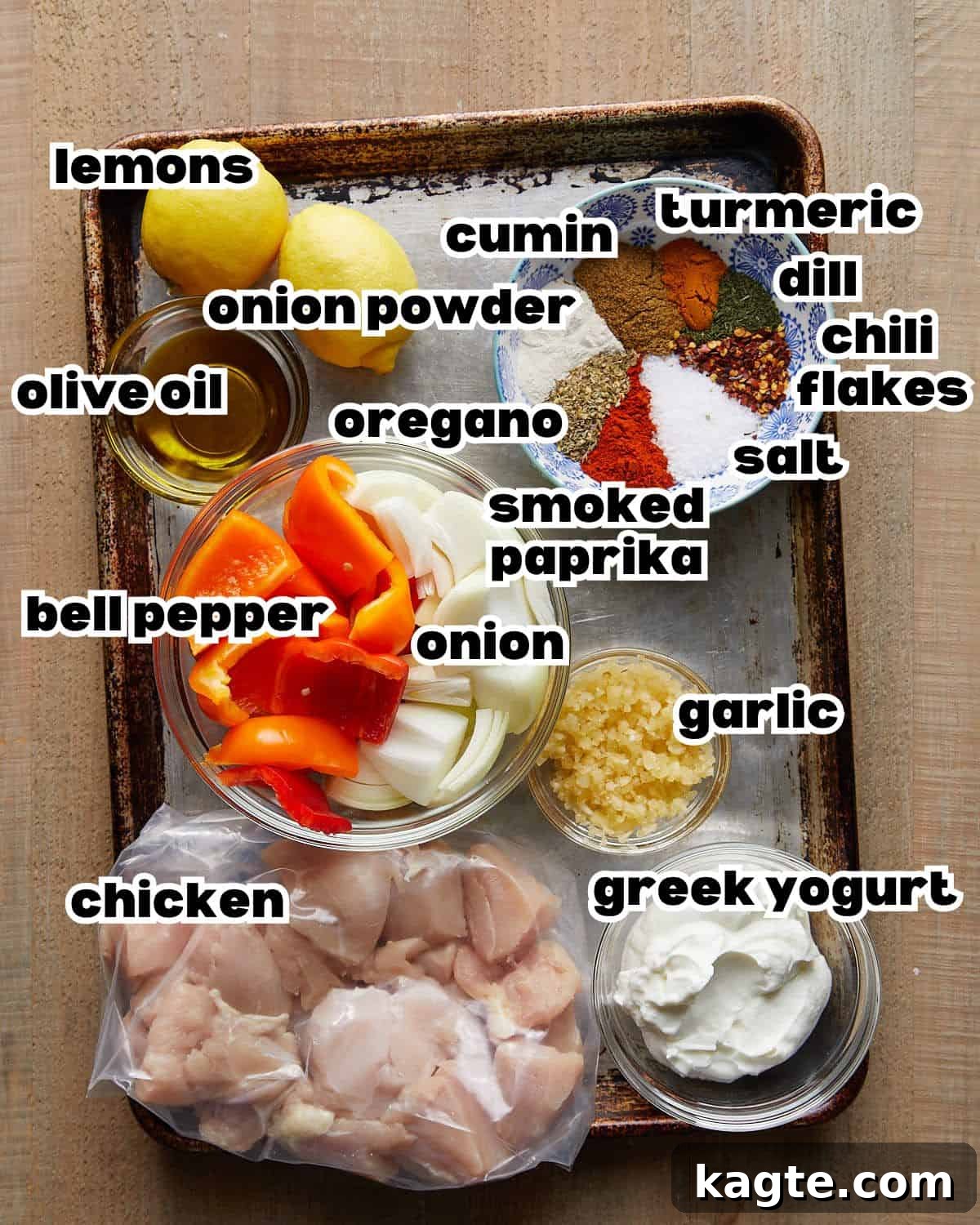 Simple Oven Roasted Chicken Kabobs 3 Overhead image of all ingredients laid out for making chicken kabobs in the oven, including Greek yogurt, chicken breast, bell peppers, onions, lemon, garlic, and various spices.