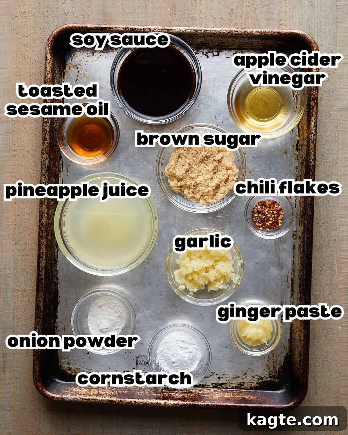 Tropical Pineapple Teriyaki Glaze 3 Overhead image of fresh ingredients laid out on a white surface, including minced garlic, ginger paste, red chili flakes, a can of pineapple juice, a bottle of soy sauce, brown sugar, and a bowl of cornstarch slurry, ready for making pineapple teriyaki sauce.