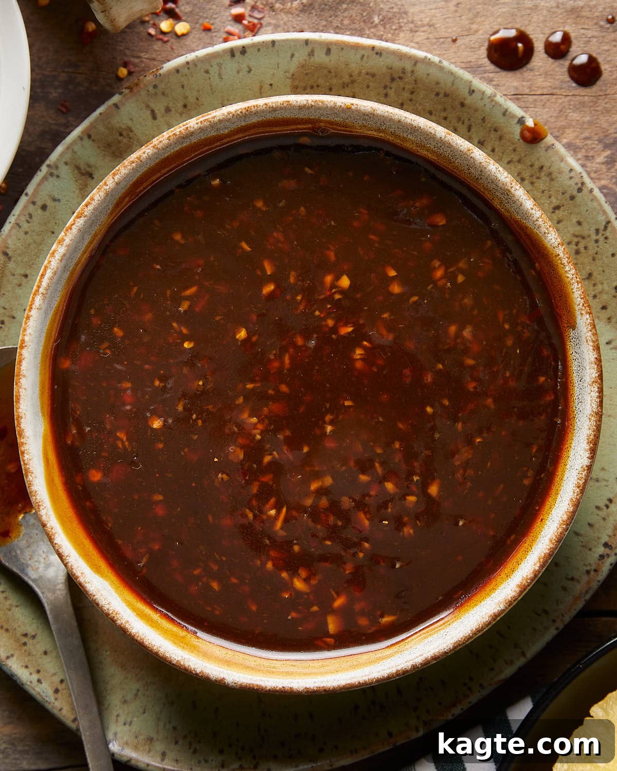 Tropical Pineapple Teriyaki Glaze 5 Up close overhead image of a ceramic bowl filled with glossy homemade pineapple teriyaki sauce, garnished with toasted sesame seeds and finely chopped green onions, ready to be enjoyed.