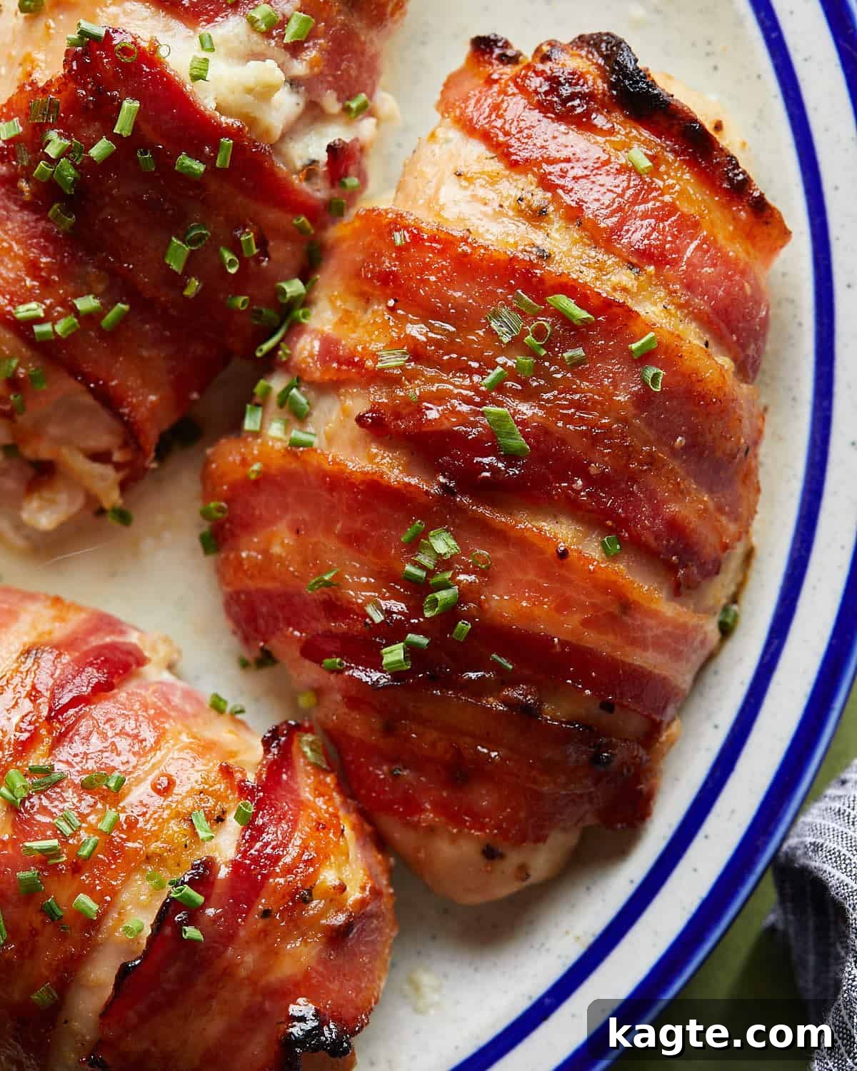 Crispy Bacon-Wrapped Stuffed Chicken Breast, Oven-Baked 2 Up close overhead image of bacon wrapped chicken breasts with garnish.
