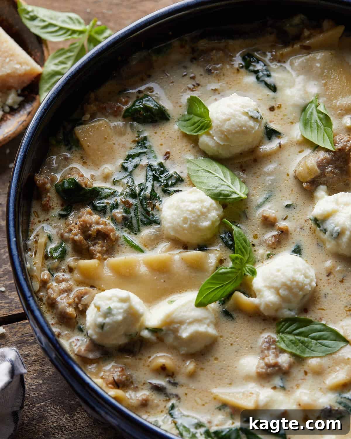 Velvety White Lasagna Soup with Zesty Italian Sausage 5 A close-up overhead shot of a bowl of white lasagna soup, showing the creamy texture, noodles, sausage, and spinach, with fresh basil garnish.
