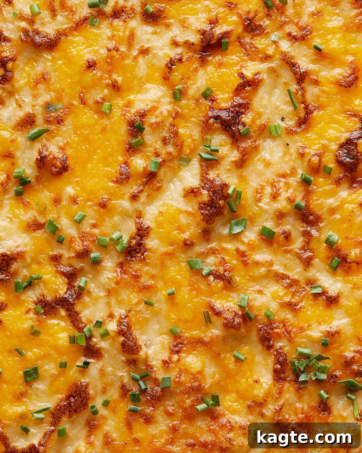 Effortless Gooey Cheesy Potatoes 5 Up close and overhead image of cheesy mashed potatoes with garnish.