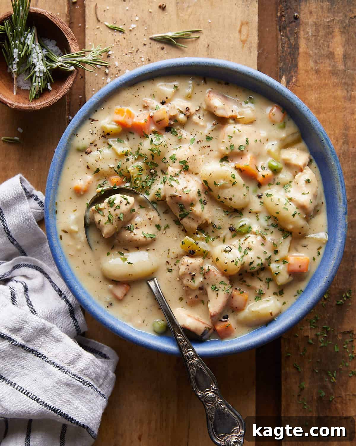 Overhead image of chicken and dumplings with gnocchi in blue bowl with silver spoon.