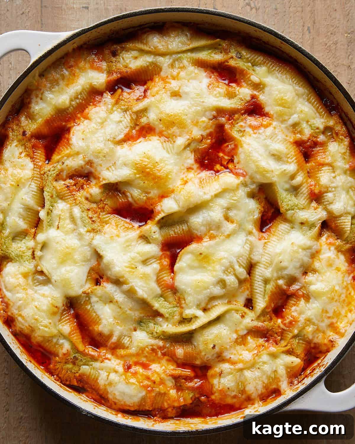 Overhead view of baked stuffed shells fresh from the oven, cheesy and golden in a white baking dish
