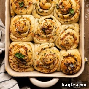 Close-up of a single Cheesy Garlic Herb Butter Roll, showing the spiral layers of dough, cheese, and herbs.