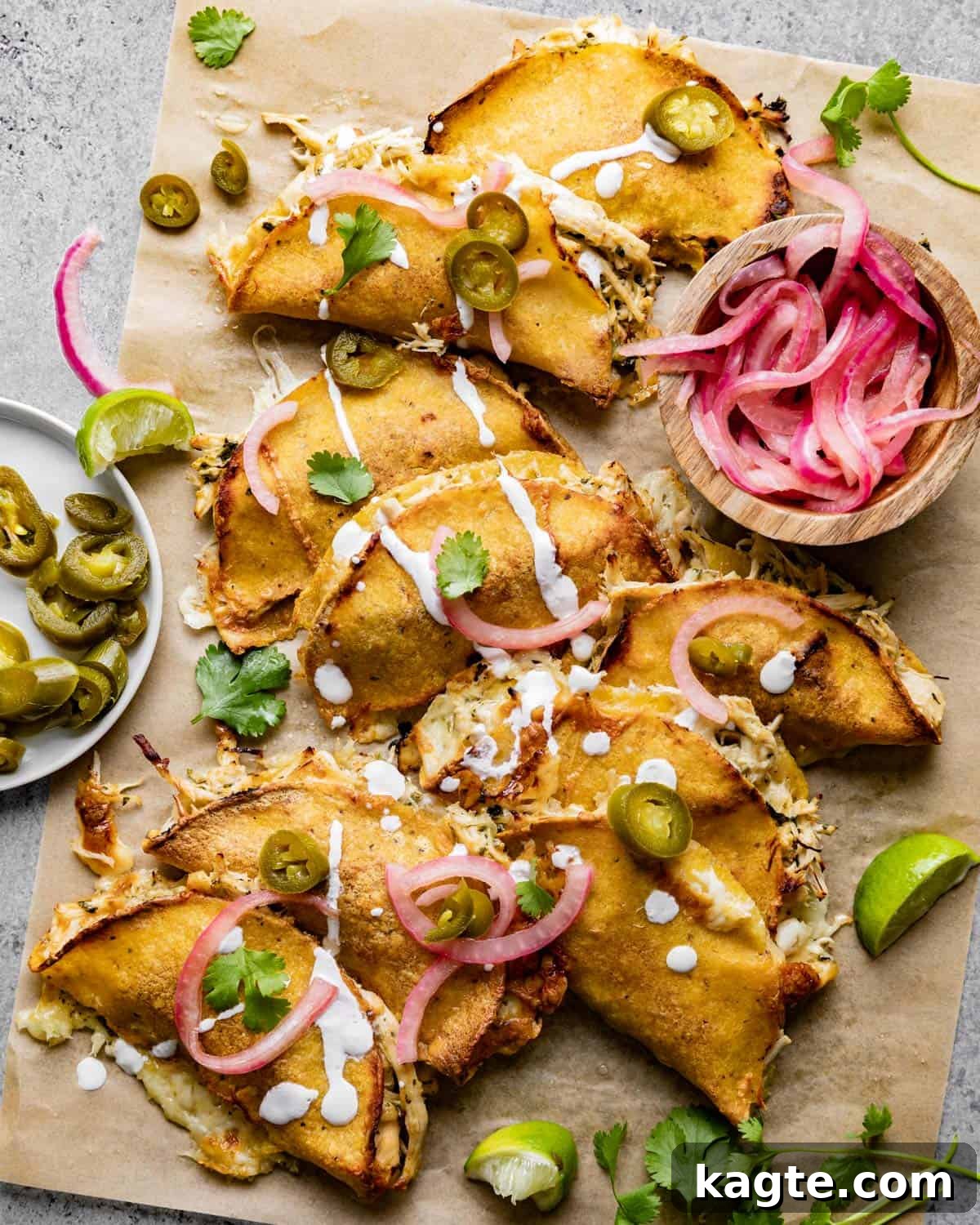 Oven-Fresh Cilantro Lime Tacos 2 Overhead shot of crispy baked cilantro lime chicken tacos garnished with fresh cilantro and pickled onions on parchment paper.