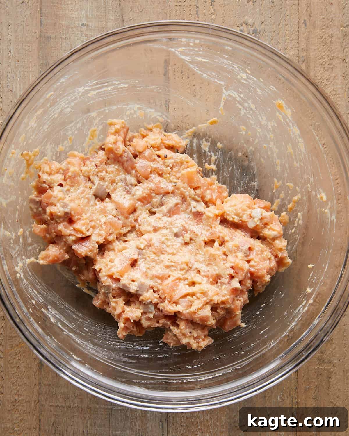 Flavor-Packed Salmon Burgers with Zesty Sriracha Aioli 6 Overhead image of chopped salmon pieces mixed with salmon paste, showing a chunky, well-combined mixture ready to shape into patties for Asian salmon burgers.