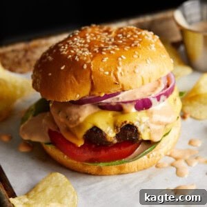 Juicy Grilled Hamburger Recipe for Perfect Backyard Burgers 7 Finished cheeseburger on a sesame bun with lettuce, tomato, and red onion.