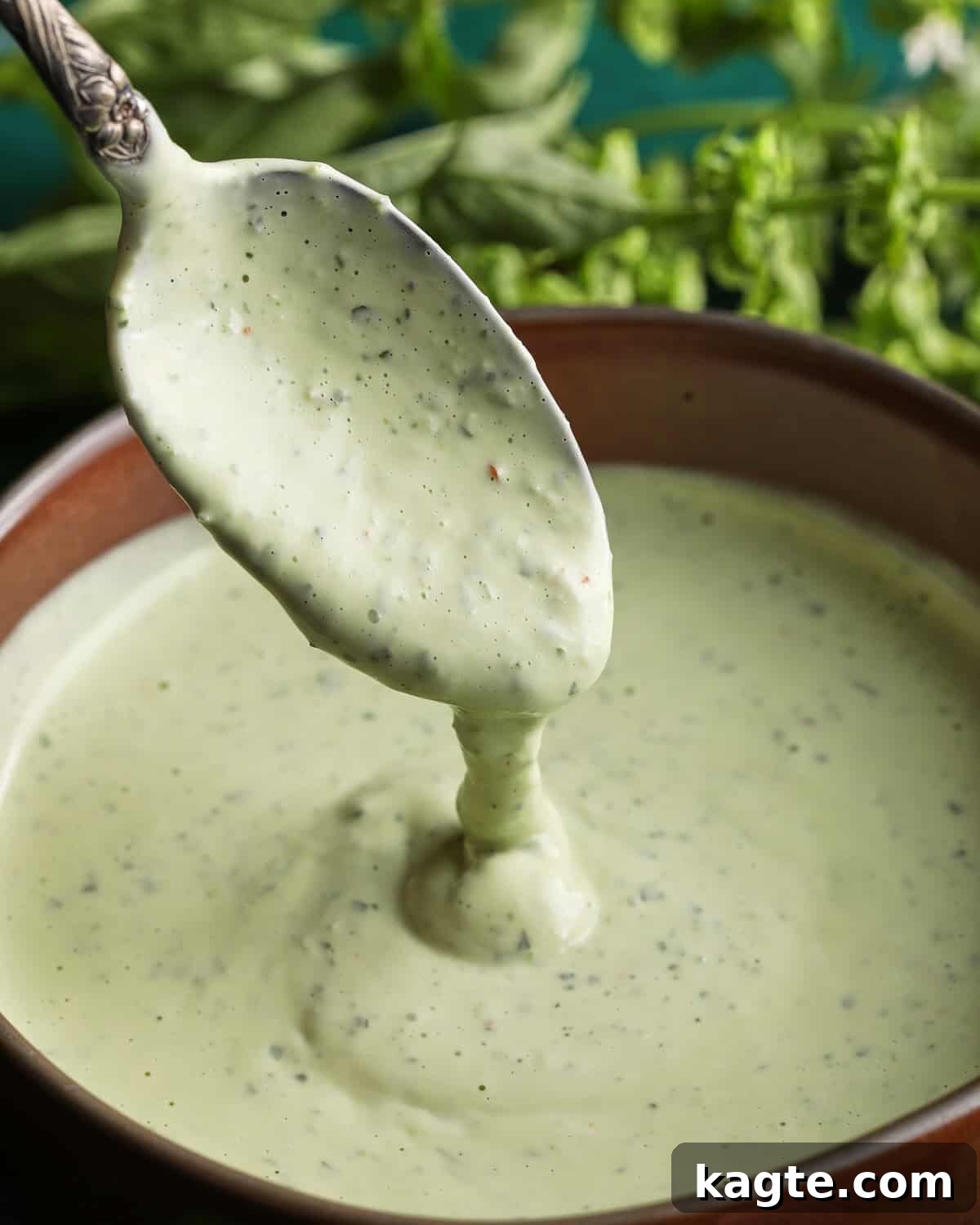 Creamy Homemade Basil Aioli 2 Spoon lifting creamy basil aioli from a small bowl with fresh basil in the background.