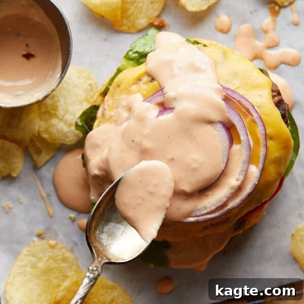 Creamy Homemade Basil Aioli 8 Gold spoon spreading burger sauce onto a burger.
