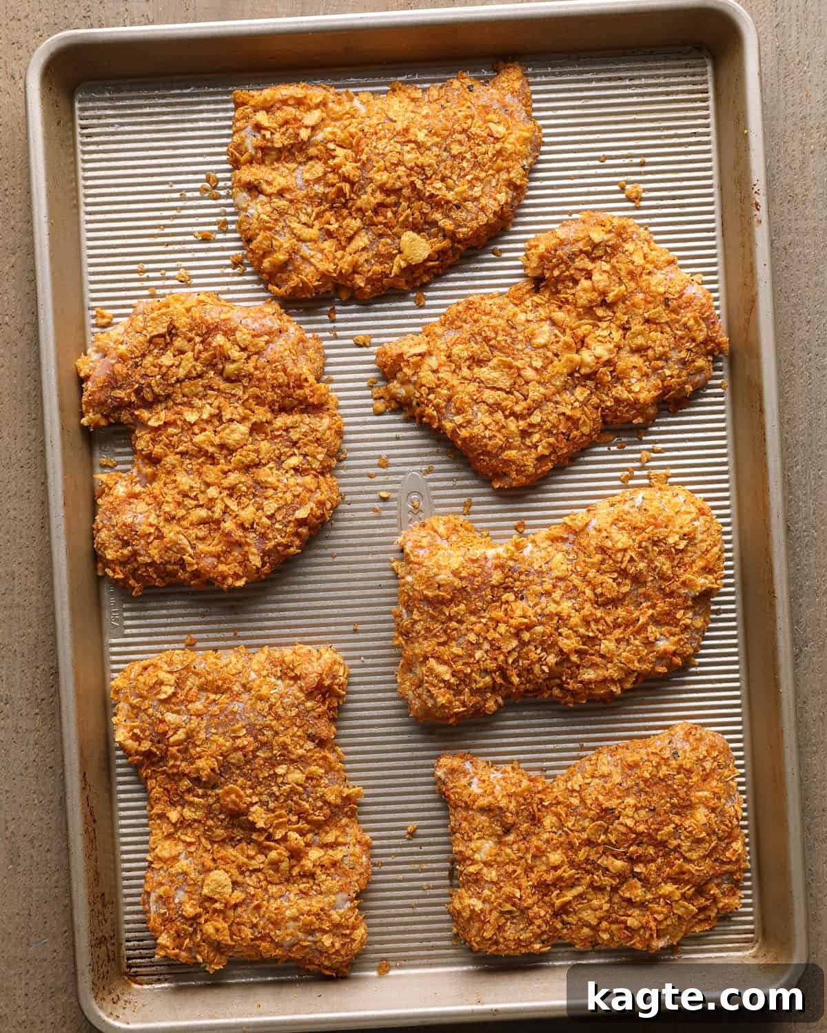 Crispy Baked Cornflake-Crusted Chicken Thighs 7 Six cornflake-coated chicken thighs arranged on a baking sheet before baking.