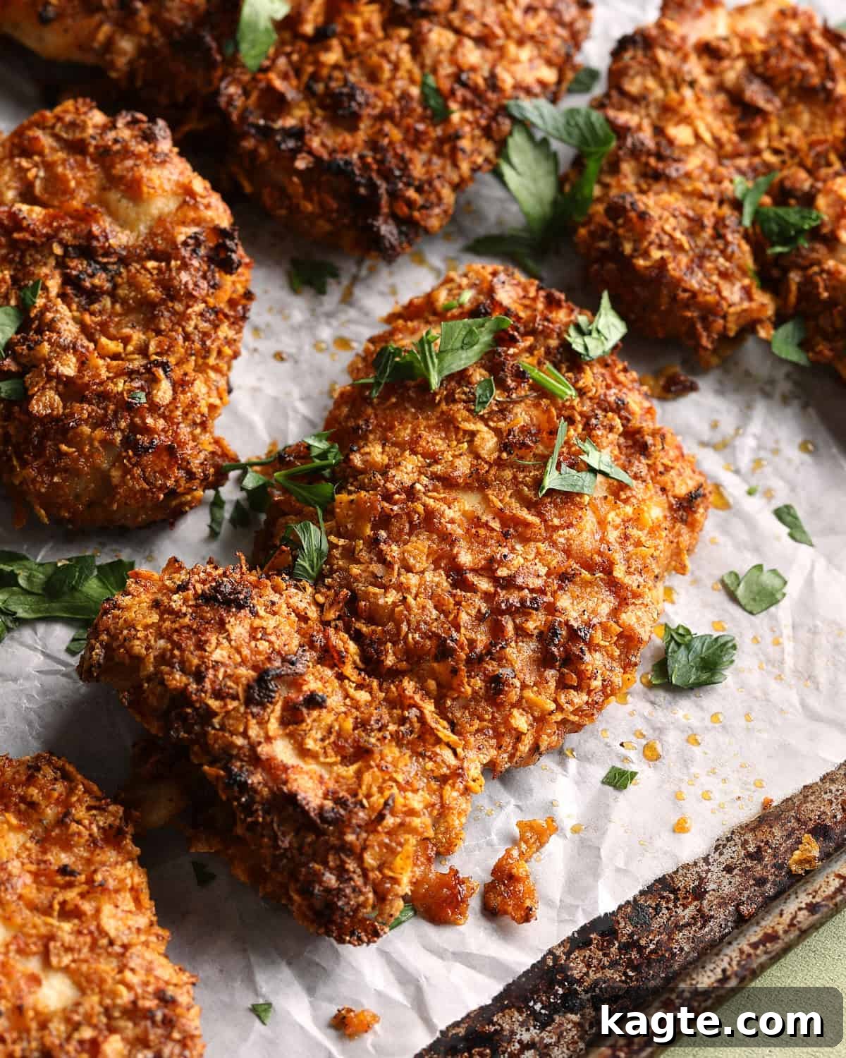 Crispy Baked Cornflake-Crusted Chicken Thighs 9 Close-up of crispy baked cornflake chicken thighs with a browned Parmesan-cornflake coating and chopped parsley.