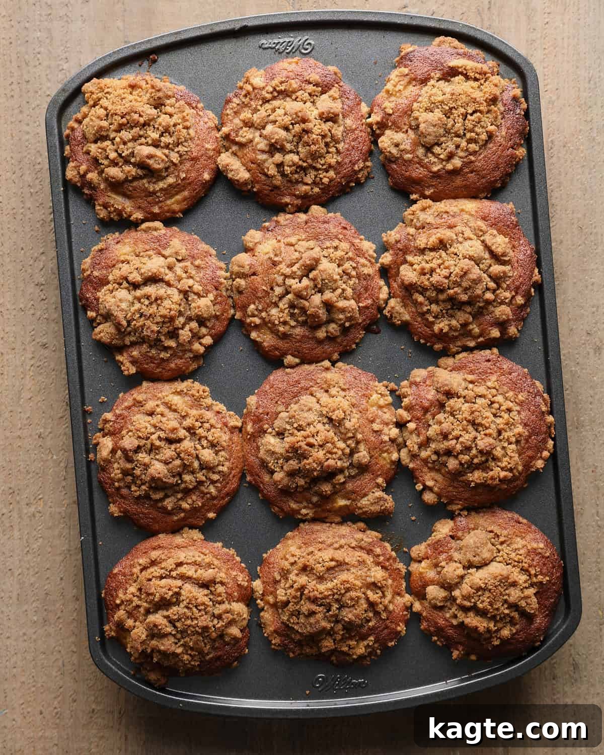 Apple Cider Muffins with Cinnamon Crumb Topping 8 Twelve baked apple cider muffins with tall browned tops and cinnamon crumb in the muffin pan.