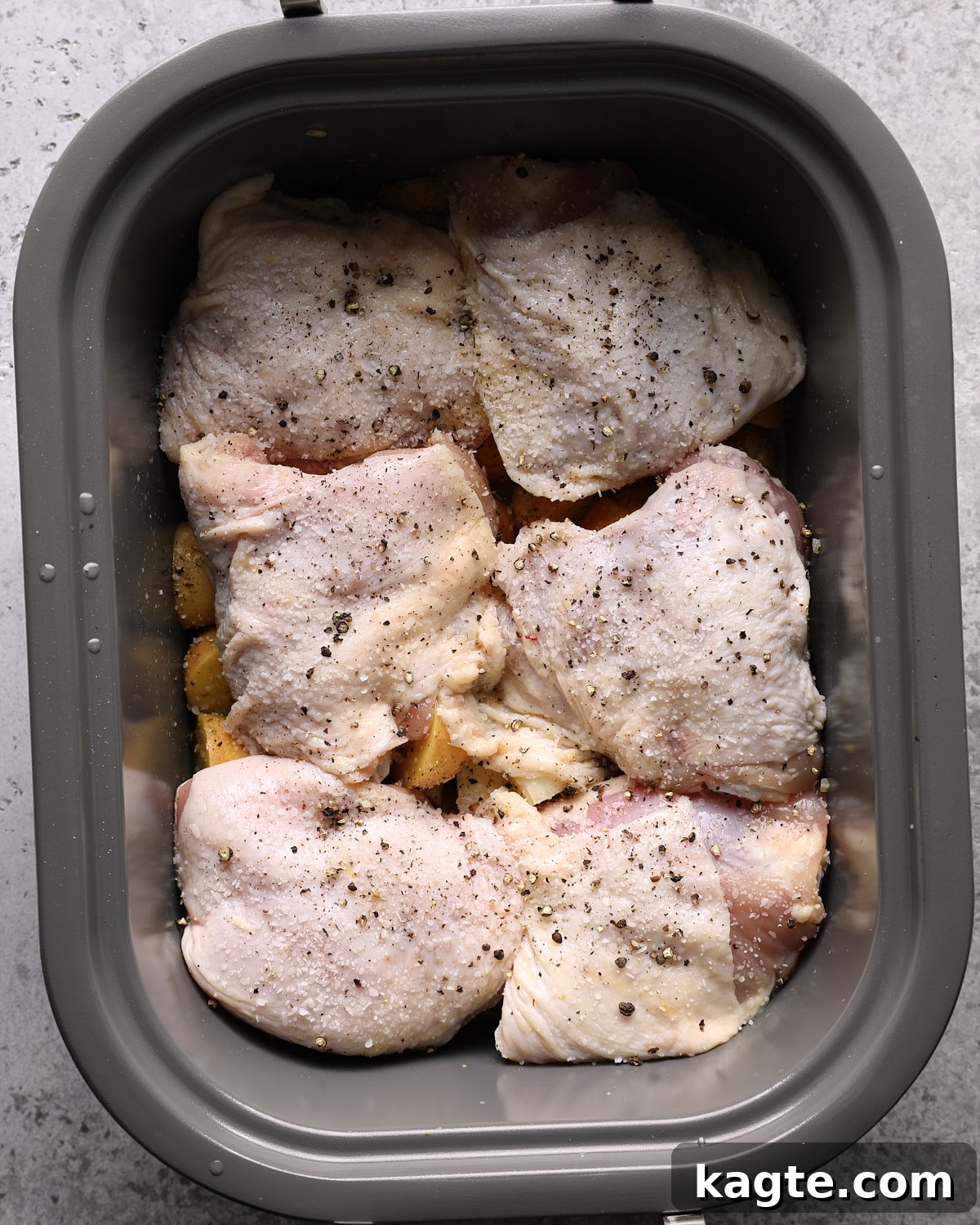 Slow Cooker Greek Lemon Chicken and Potatoes 6 Raw bone-in chicken thighs arranged skin-side up over potatoes in a slow cooker.