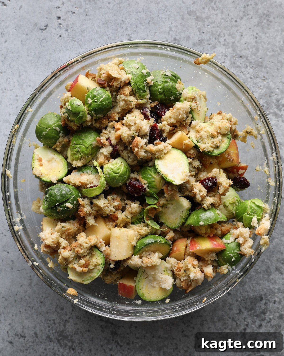 Sheet Pan Roasted Chicken with Herb Stuffing 4 Stuffing mixed with halved Brussels sprouts, diced apple, dried cranberries, and Parmesan in a glass bowl.